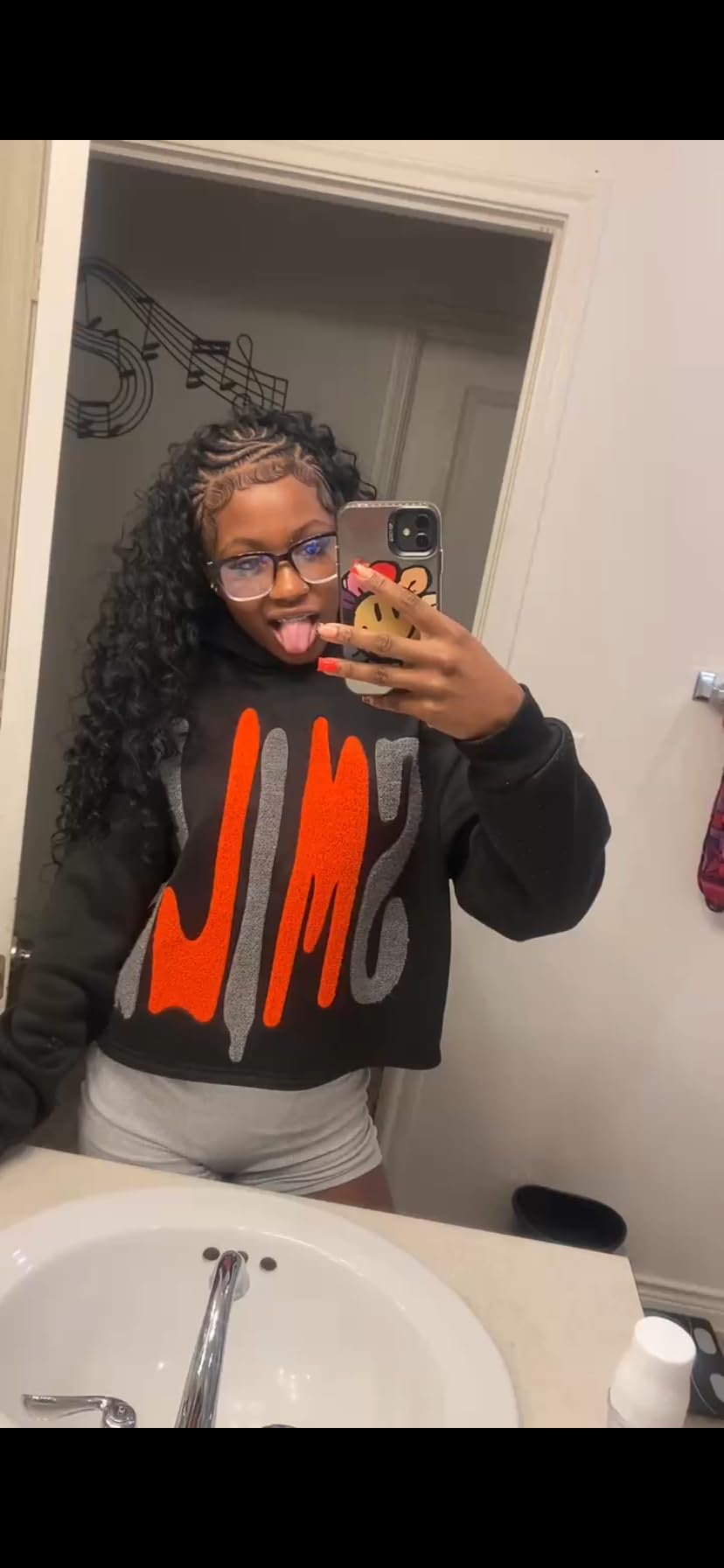 Customer mirror selfie wearing a half up style with braided front sections and long curly Organique bundles down the back