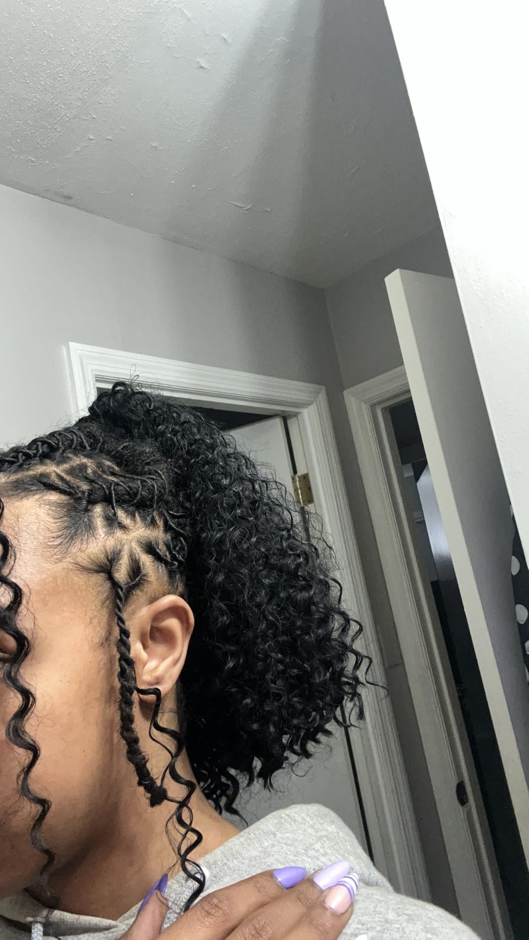 Side view of a curly ponytail with knotless braids at the hairline and the curl pattern still separated