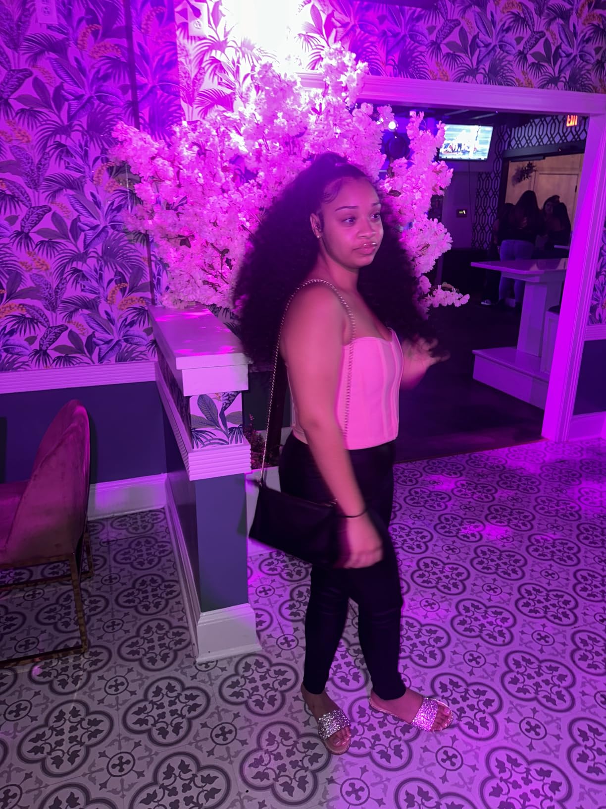 Big curly set worn out at a venue under pink lighting, the hair falling well below the shoulders