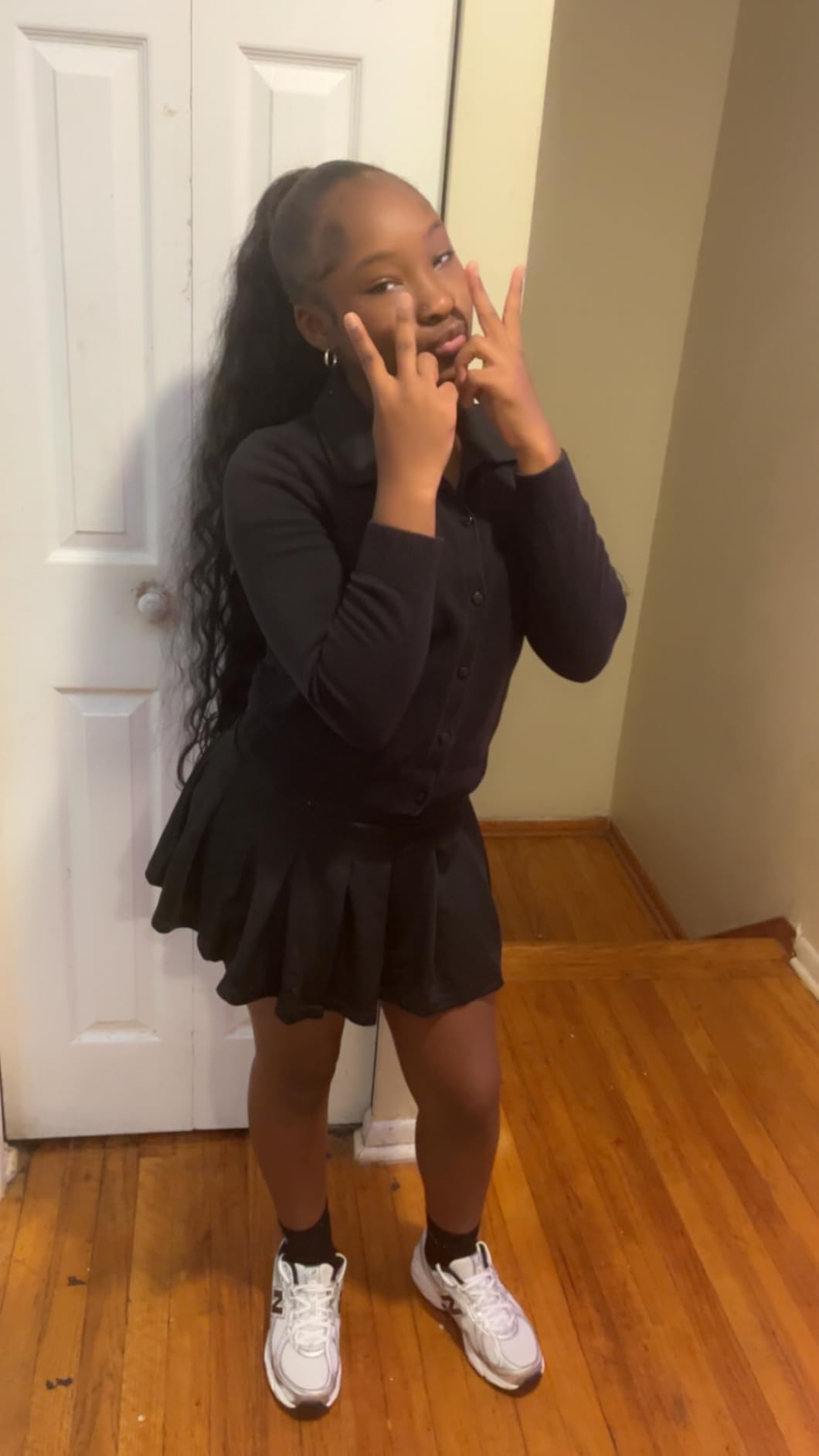High curly ponytail reaching past the waist, worn with a black skirt set
